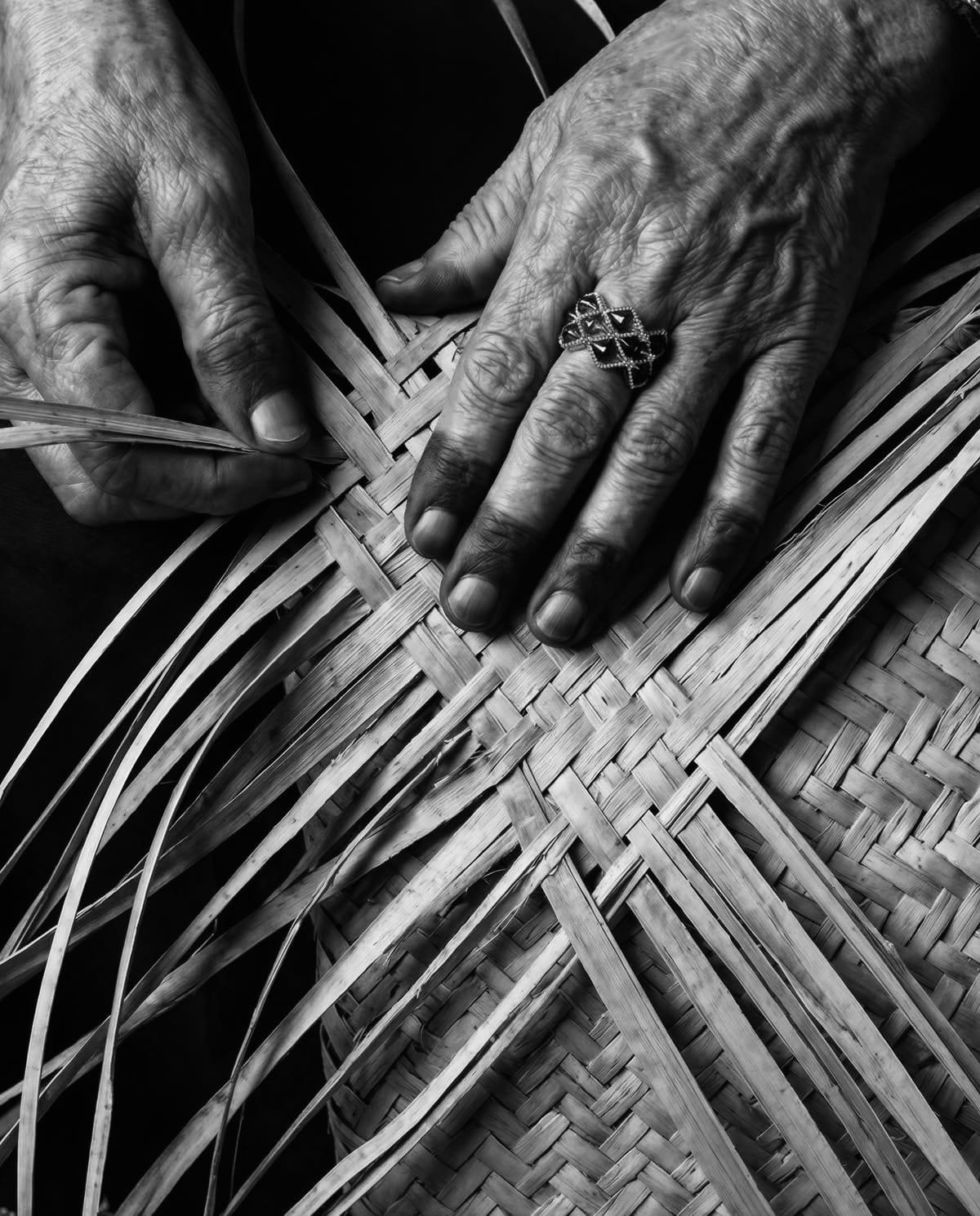 An artisan's hands weaving Sital Pati strips